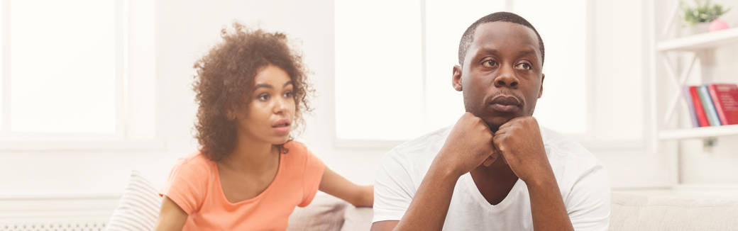 man and woman sitting on the couch looking troubled